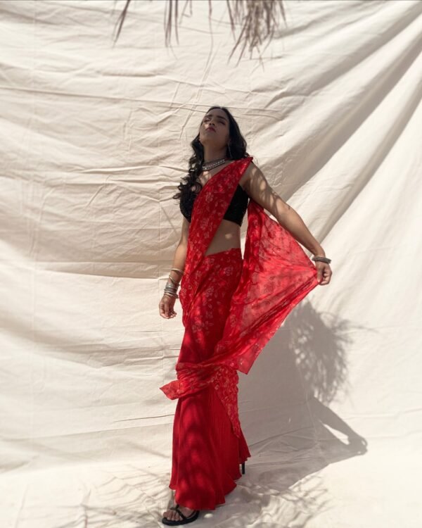 Pre-draped, slim fit saree in crimson chiffon with sequin embroidery. Styled with black sleeves sequin blouse