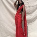 Pre-draped, slim fit saree in crimson chiffon with sequin embroidery. Styled with black sleeves sequin blouse. 