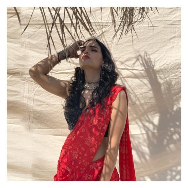 Pre-draped, slim fit saree in crimson chiffon with sequin embroidery. Styled with black sleeves sequin blouse. 